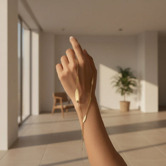 Hand wearing a gold leaf bracelet with a blurred background