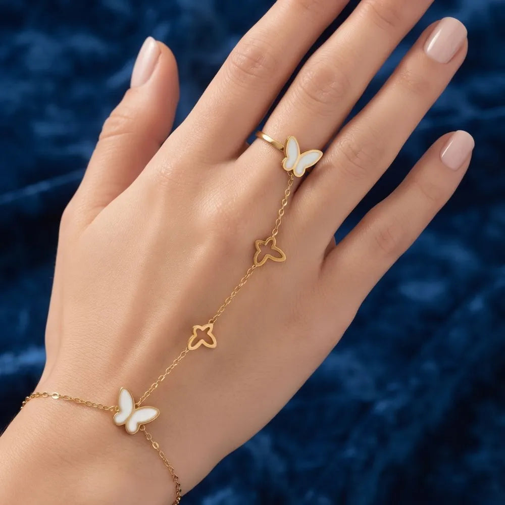 Close-up of a woman's hand wearing the Golden Naqsh 18K gold plated butterfly hand chain bracelet connected to an adjustable ring