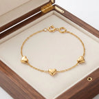 Close-up view of a woman wearing the Golden Naqsh 18K gold plated 3 heart chain bracelet on her wrist for a chic minimalist look