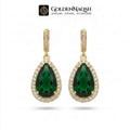 A pair of gold teardrop-shaped drop earrings featuring deep green teardrop gemstones surrounded by small clear stones, shown on a white background with the GoldenNaqsh brand logo at the top.