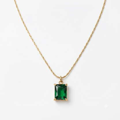 Gold necklace with a green gemstone pendant on a white background