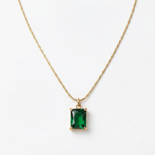Gold necklace with a green gemstone pendant on a white background