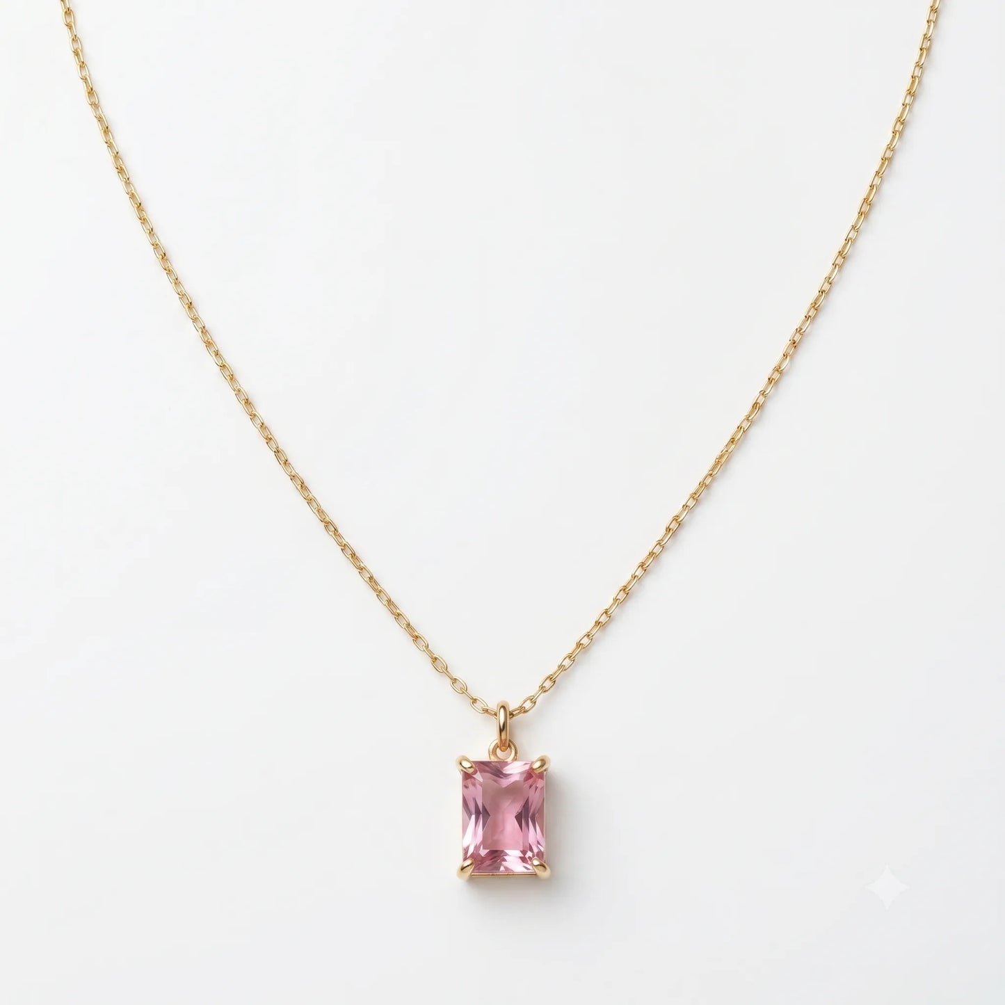 Gold necklace with a pink gemstone pendant on a white background