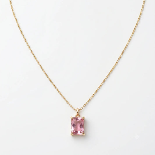 Gold necklace with a pink gemstone pendant on a white background