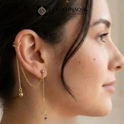 A close-up side profile of a woman wearing a gold ear cuff with delicate chain drapes and small dangling charms. The brand name 'COLDENNAO' is visible as a watermark at the top.