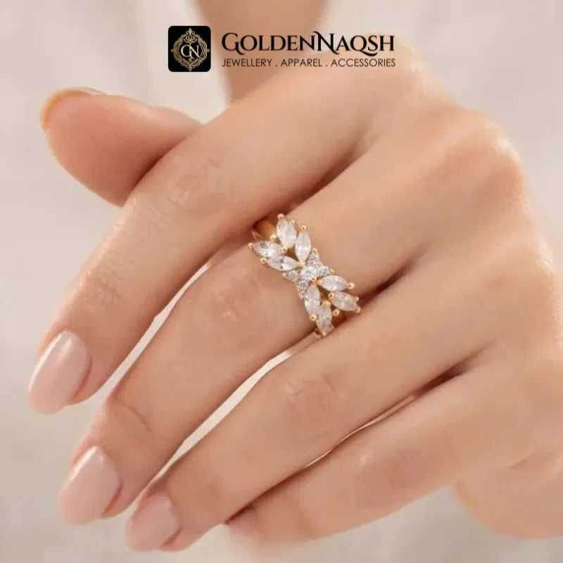 A close-up of a hand wearing a gold ring with marquise-cut clear stones in a floral cluster design. The GoldenNaqsh brand logo is visible at the top of the image.