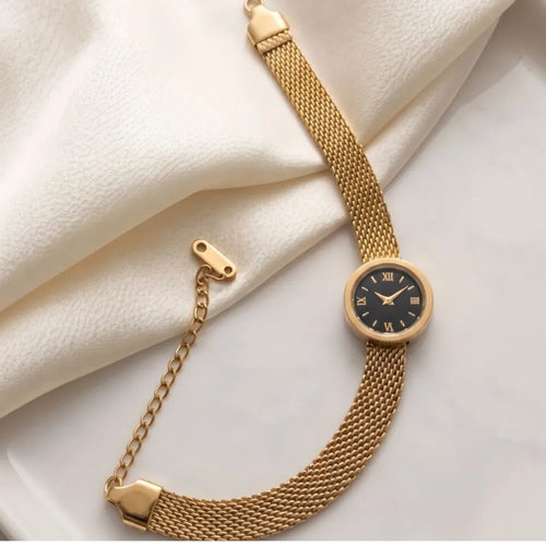 Golden Naqsh Watch Bracelet featuring a gold mesh chain strap and a black mini watch face with Roman numerals resting on white silk