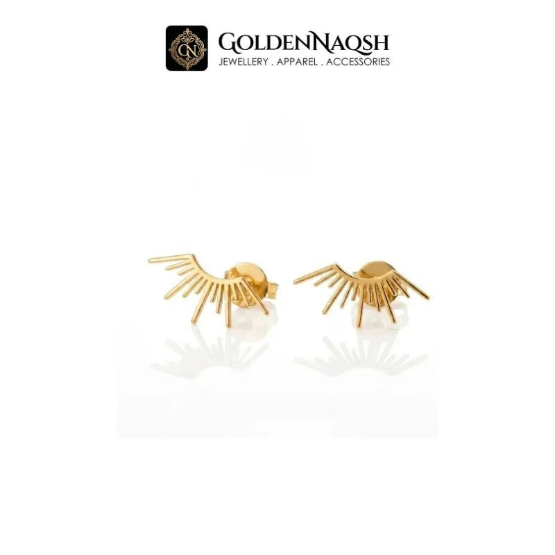 A pair of gold eyelash stud earrings with radiating prongs, displayed on a clean white background with a reflection below. The brand logo 'GOLDENNAQSH' is visible at the top of the image.