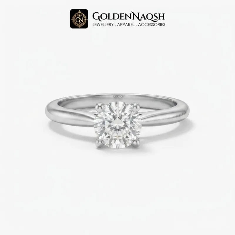 A classic solitaire engagement ring featuring a round brilliant-cut diamond set in a polished silver-colored metal band, presented on a clean white background with the GoldenNaqsh brand logo at the top.