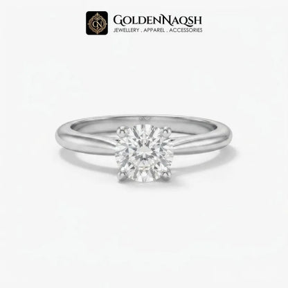 A classic solitaire engagement ring featuring a round brilliant-cut diamond set in a polished silver-colored metal band, presented on a clean white background with the GoldenNaqsh brand logo at the top.